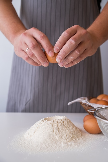 Foto gratuita chef rompiendo un huevo en harina