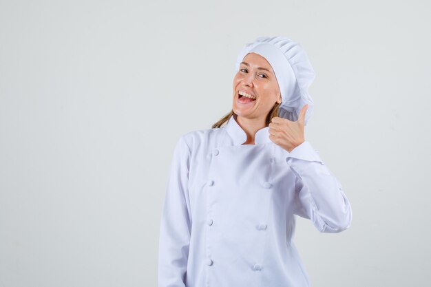 Chef de sexo femenino mostrando el pulgar hacia arriba en uniforme blanco y mirando feliz. vista frontal.