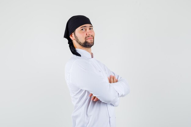 Chef de sexo masculino de pie con los brazos cruzados en uniforme blanco y mirando confiado. vista frontal.