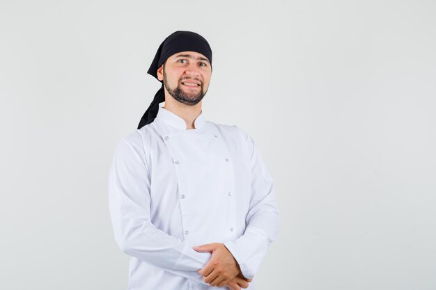 Chef de sexo masculino de pie mientras está en uniforme blanco y parece alegre. vista frontal.