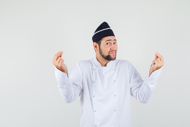 Chef de sexo masculino en uniforme blanco mostrando gesto de meditación y mirando relajado, vista frontal.