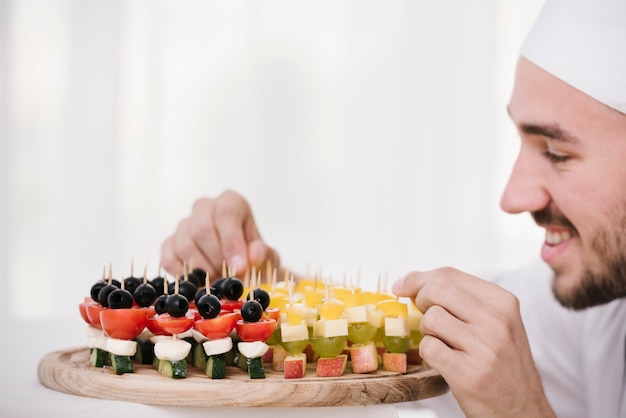 Chef sonriente organizando un plato de aperitivos