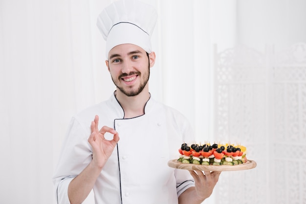 Chef sonriente con sombrero con plato