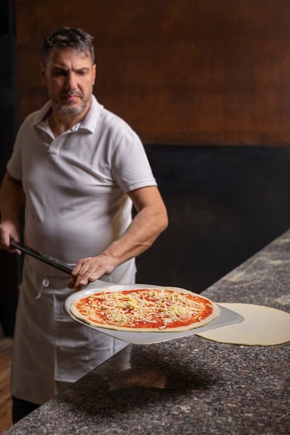 Foto gratuita chef de tiro medio preparando pizza