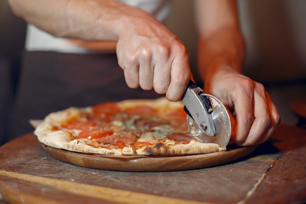 Foto gratuita chef en uniforme blanco prepara una pizzaa