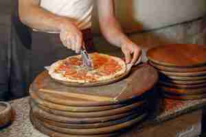 Foto gratuita chef en uniforme blanco prepara una pizzaa