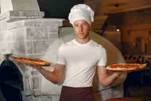 Foto gratuita chef en uniforme blanco prepara una pizzaa