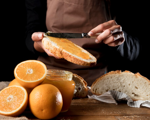 Foto gratuita chef untando mermelada de naranja sobre pan