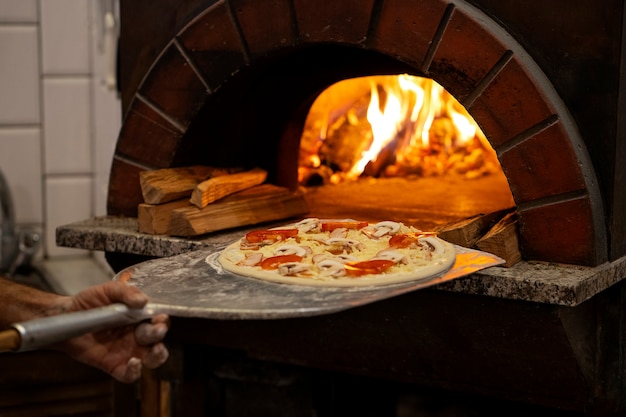 Chef de vista lateral horneando deliciosa pizza