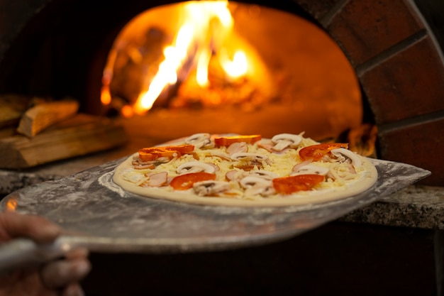 Chef de vista lateral horneando deliciosa pizza