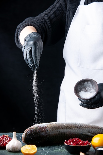 Foto gratuita chef de vista superior con guantes sal espolvoreado sobre semillas de granada de pescado fresco en un tazón en la mesa