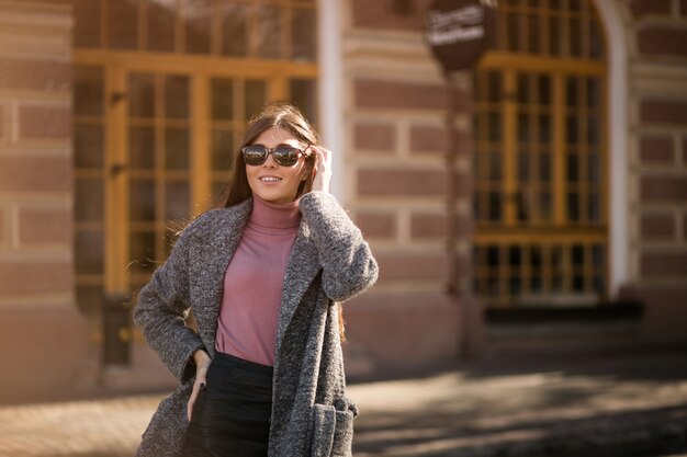 Chica en abrigo de pie en la calle