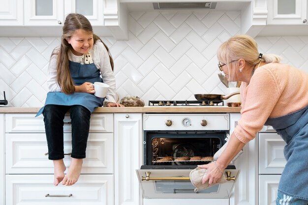 Chica y abuela cocinando plano medio