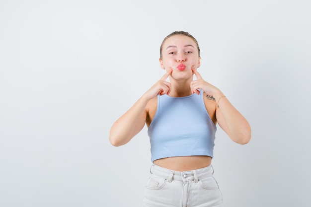 chica aburrida está mostrando sus mejillas sobre fondo blanco.