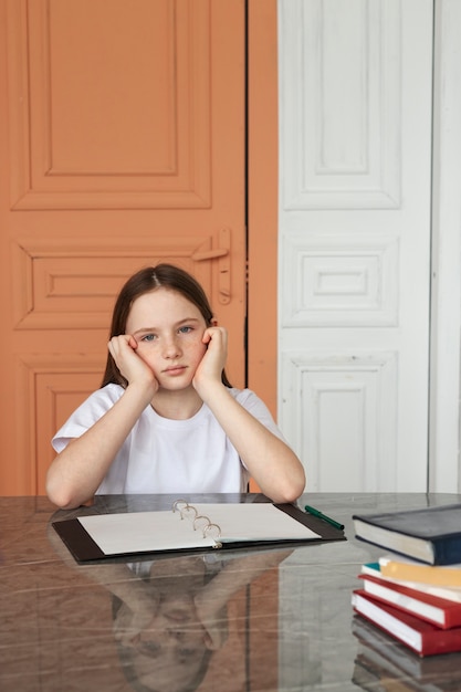 Chica aburrida de tiro medio sentada en el escritorio