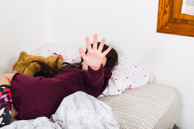 Chica acostada en la cama gesticular señal de stop