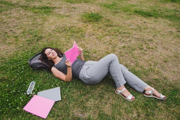 Chica acostado en el cuaderno de lectura de hierba