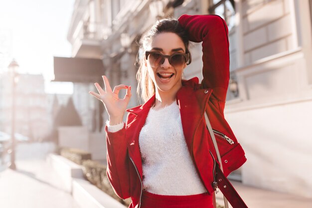 Chica activa en grandes gafas de sol divirtiéndose en la calle