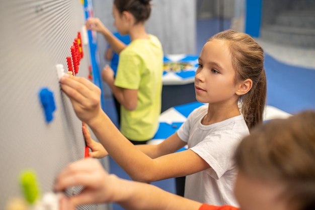 Foto gratuita chica adjuntando pieza de lego a la pared