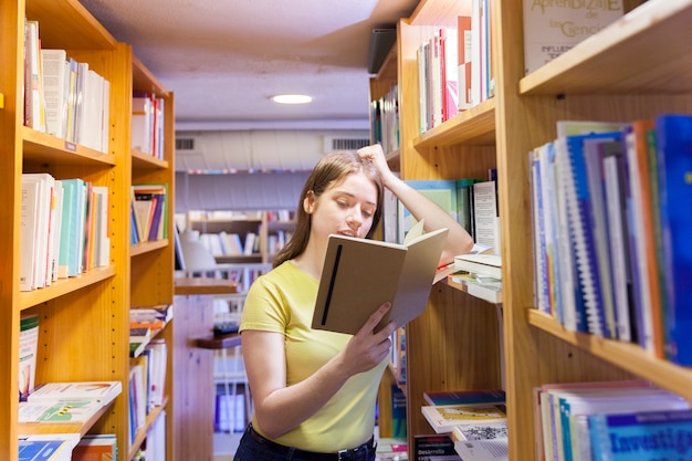 Chica adolescente apoyándose en librería y leyendo