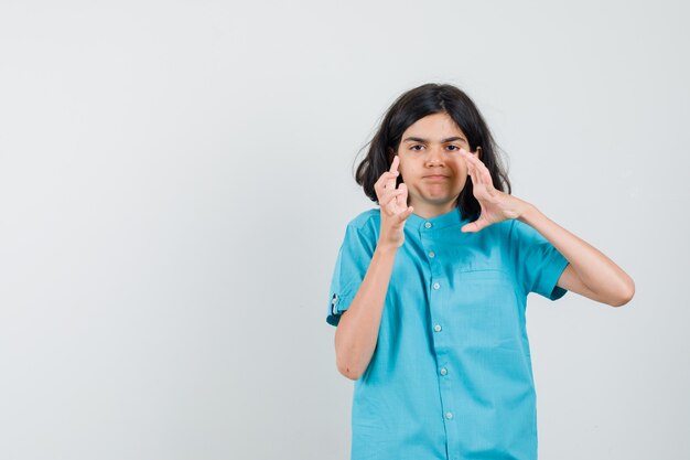 Chica adolescente en camisa azul pensando en estrangular a alguien y mirando nervioso