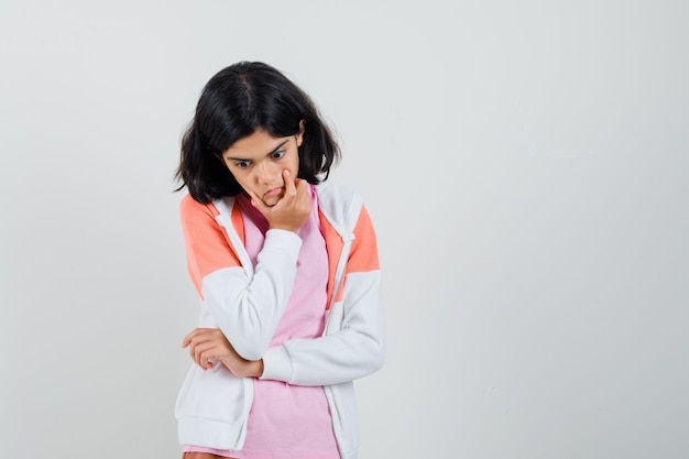 Chica adolescente en chaqueta, camisa rosa mirando hacia abajo y mirando pensativo.