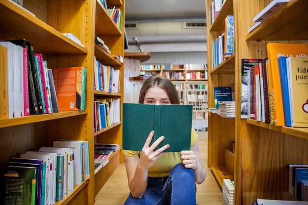 Chica adolescente cubriendo la cara con el libro