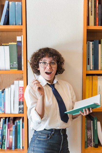 Foto gratuita chica adolescente emocionada tener idea en la biblioteca