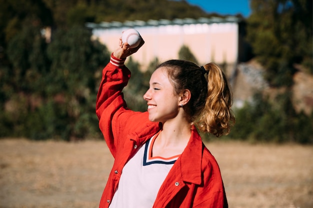 Chica adolescente feliz con pelota para beisbol