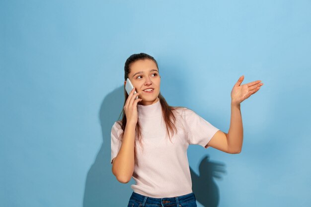 Chica adolescente hablando por teléfono inteligente, sonriendo