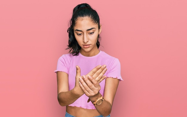 Foto gratuita chica adolescente hispana con frenos dentales con ropa informal que sufre dolor en las manos y los dedos inflamación de la artritis