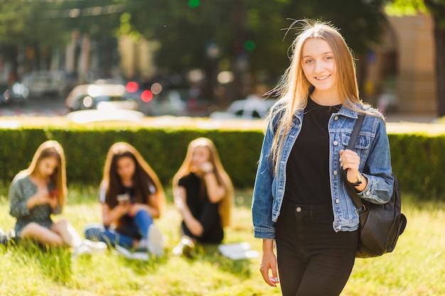 Chica adolescente con mochila cerca de amigos