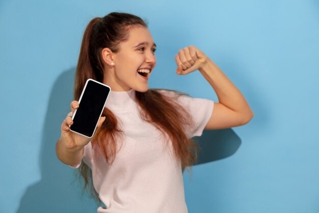 Foto gratuita chica adolescente mostrando la pantalla del teléfono, parece ganador