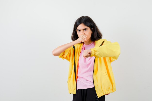 Chica adolescente de pie en pose de lucha en camiseta, chaqueta y mirando enfocado, vista frontal.