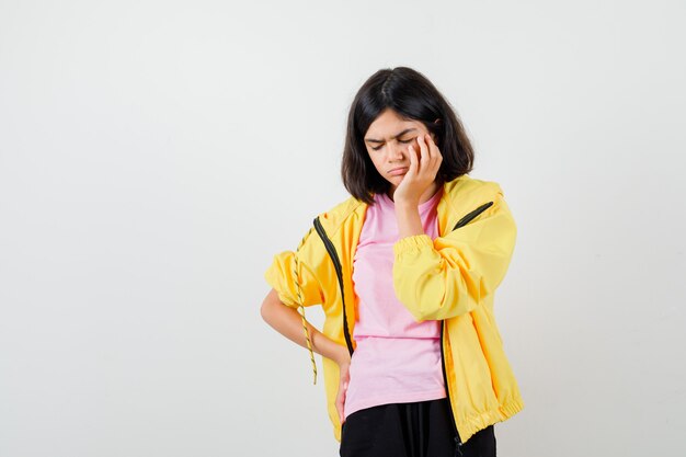 Chica adolescente de pie en pose de pensamiento en camiseta, chaqueta y mirando perplejo. vista frontal.