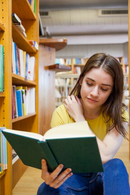 Chica adolescente rascarse hombro y libro de lectura