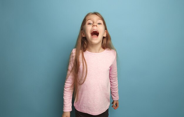 La chica adolescente rubia emocional tiene una mirada de felicidad y gritos. Tiro del estudio