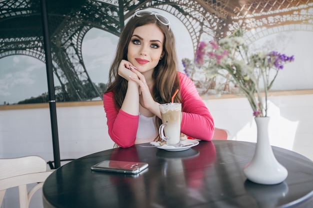 Chica adolescente sentada en una mesa de cristal con un batido de chocolate