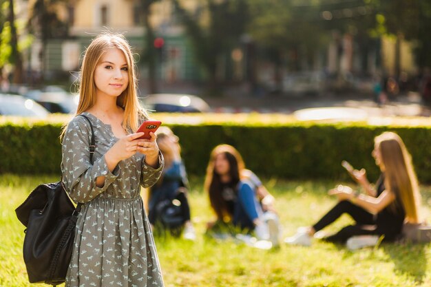 Chica adolescente con smartphone mirando a cámara