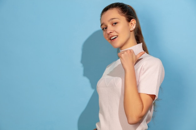 Chica adolescente sonriendo, apuntando hacia atrás