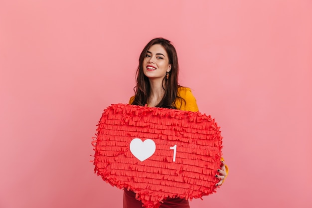 Foto gratuita chica adolescente en traje brillante está sonriendo, sosteniendo el cartel rojo 