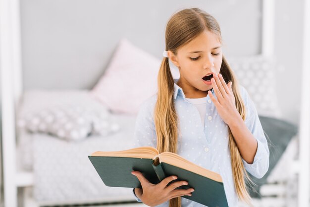 Chica adorable cansada leyendo un libro