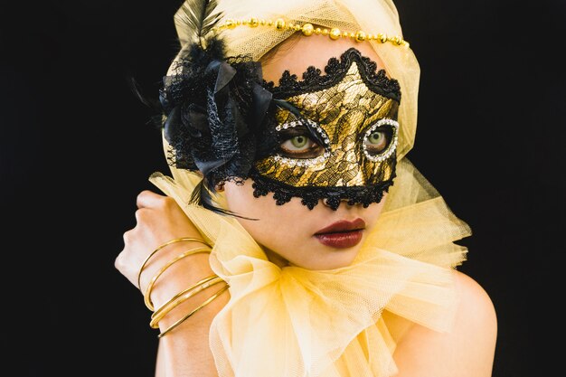 Chica con un adorno amarillo en la cabeza y una máscara veneciana