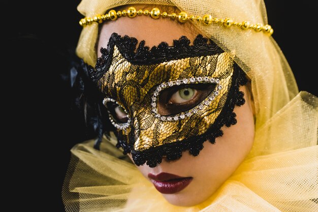 Chica con un adorno amarillo en la cabeza y una máscara veneciana