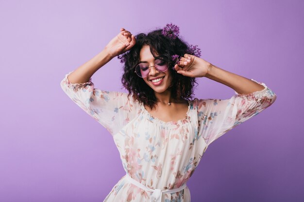 Chica africana romántica bailando con los ojos cerrados. foto de mujer joven morena atractiva con flores en el pelo.