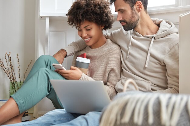 Chica afro positiva feliz de hacer compras en línea en cellualr