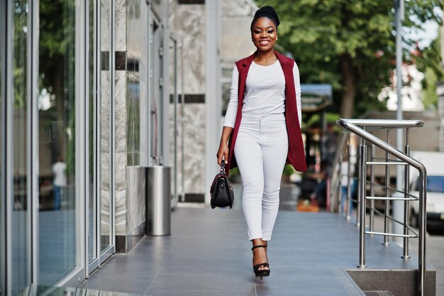 Chica afroamericana con bolso de mano planteada al aire libre de la ciudad de steets