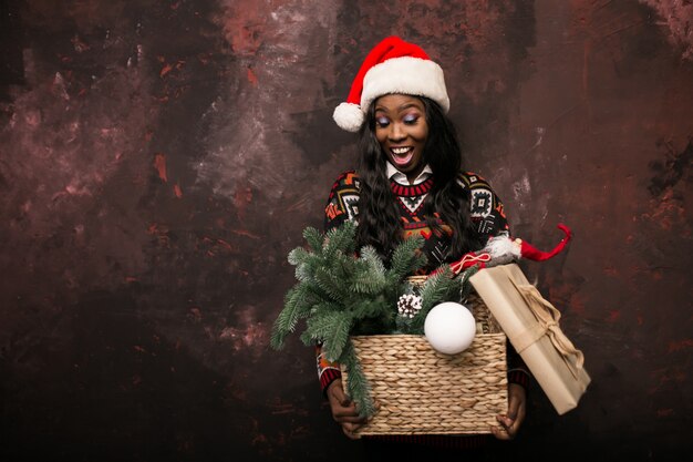 Chica afroamericana con decoraciones de Navidad en una caja