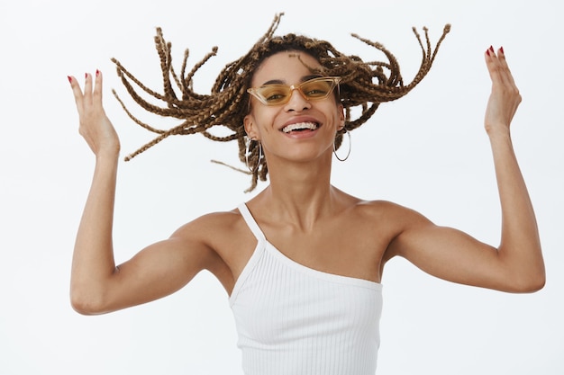 Chica afroamericana con estilo despreocupada en gafas de sol que se siente relajada y feliz