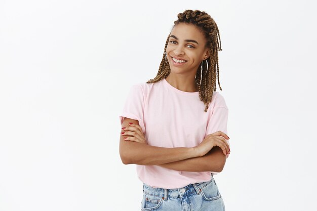 Chica afroamericana segura elegante en camiseta rosa sonriendo feliz